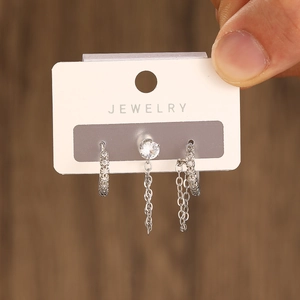 Detail of silver earring set featuring zircon studs and elegant chain link accents