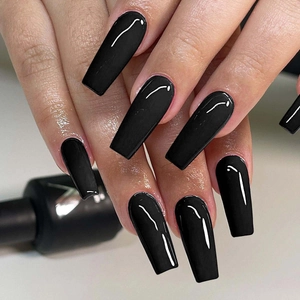 Detailed close-up of glossy black coffin-shaped press-on nails on hands with a sleek finish