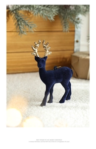 Detail of navy blue flocked reindeer with golden glitter antlers on snow scene