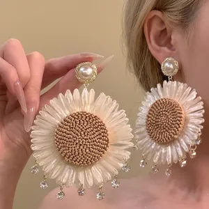Detail of sunflower tassel earrings with woven petals and sparkling crystal pendants