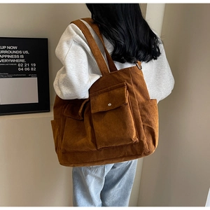 Detail of dark brown corduroy tote bag showing dual front flap pockets and soft texture