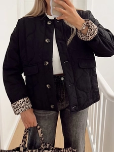 Detail of black quilted jacket featuring leopard print cuffs and metallic buttons