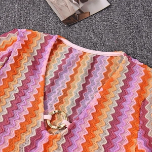 Close-up of V-neck knit dress with wavy multicolor patterns and gold ring detail