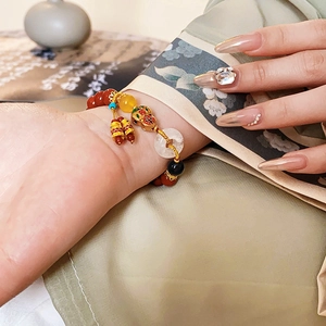 Detail of red agate beaded bracelet with gold gourd and jade safety buckle charms