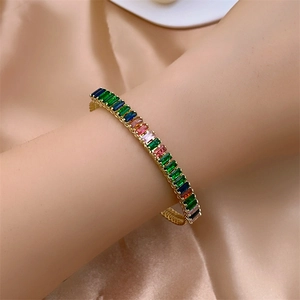 Gros plan d'un bracelet doré avec des zircons rectangulaires colorés sur fond de soie