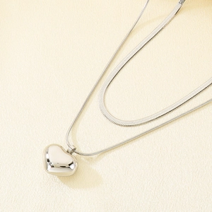 Detail showing dual-layer stainless steel snake chain with heart pendant and polished finish