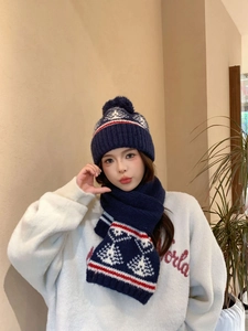 Dettaglio cappello in maglia blu scuro con motivi Fair Isle e grande pompon morbido
