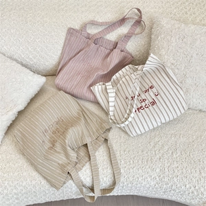 Detailed embroidery and smiley face pattern on striped canvas tote bags in a cozy setting