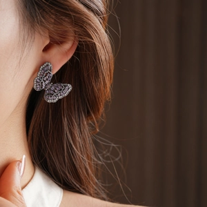 Close-up of a butterfly earring with purple zircon stones and micro-pave setting on ear