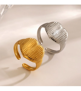 Close-up of heart-shaped striped rings in gold and silver on a minimalist stone base