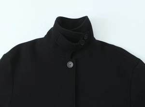 Detailed close-up of a black wool short coat featuring a stand collar and button-up design