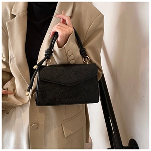 Detail of black leather handbag with embossed traditional fish and lotus floral texture