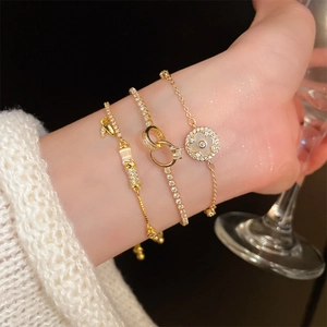 Detail of three-piece gold plated bracelet set with clover charm and zircon stones