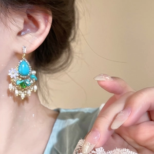 Detailed view of turquoise droplet earring with pearl tassels and vintage flower design