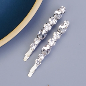 Détail de barrettes argentées avec strass brillants sur un fond gris minimaliste