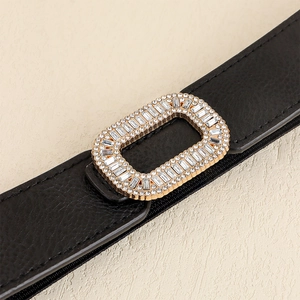 Macro detail of elastic black PU leather waist belt with sparkling gold rhinestone buckle