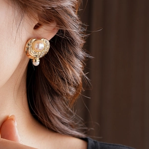 Détail de boucles d'oreilles vintage en perles dorées avec strass sur un modèle