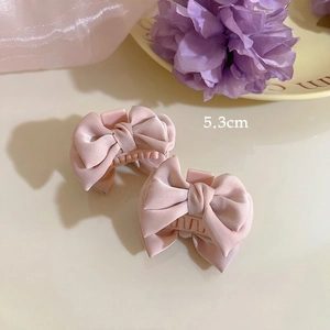 Detail view of 5.3cm pink satin bow hair clips set with two small resin shark clips
