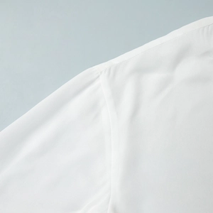 Detailed macro view of high-quality shoulder stitching on a white chiffon long sleeve blouse