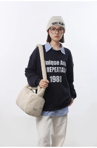 Lifestyle shot of large beige quilted nylon shoulder bag with navy blue sweatshirt