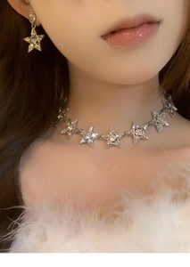 Gros plan d'un collier en forme d'étoile et boucles d'oreilles assorties avec strass brillants
