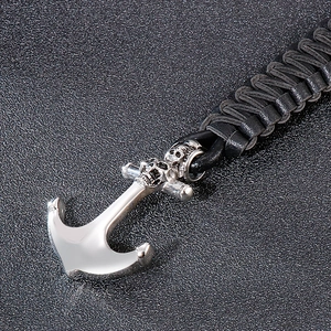 Gros plan du pendentif ancre avec crânes sur un bracelet en cuir tressé noir pour homme