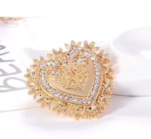 Detailed view of Baroque gold heart brooch with rhinestone bow and metal textures