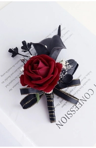 Gros plan d'une boutonnière rose bordeaux avec feuilles noires et ruban doré