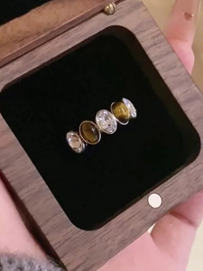 Detailed macro view of zircon and tiger eye stones in a silver ring on a wood box
