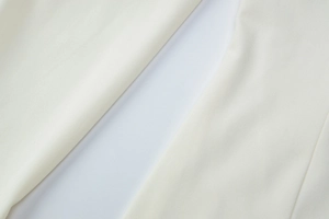 Makroaufnahme von weißem plissiertem Webstoff mit Köperstruktur auf dem Kleid