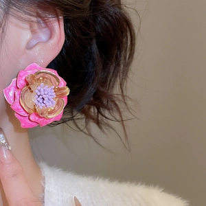 Gros plan d'un mannequin portant des boucles d'oreilles fleurs en émail rose et violet