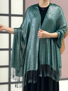 Close-up of green shimmering fabric shawl with elegant tassel fringe details on a model