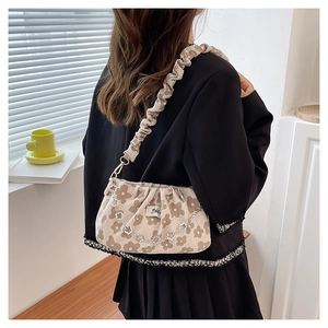 Close-up of pleated handbag with brown floral pattern and silver flower chain detail