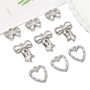 Silver plated DIY jewelry charms featuring bowknot and hollow heart pendants set on white
