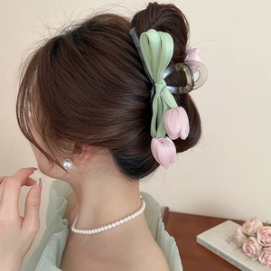 Detail of pink and green tulip ribbon hair claw clip styled on long hair in elegant bun