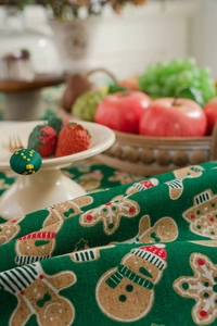 Close-up of green cotton linen tablecloth with festive gingerbread man pattern