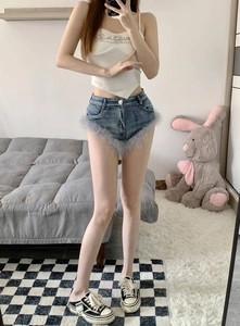Detailaufnahme der High-Waist-Denim-Shorts mit grauen Federfransen und elastischer Passform