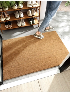 Macro detail of natural coconut fiber doormat used in entryway on grey tile floor