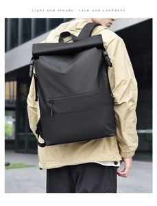 Rear view of black waterproof roll-top backpack worn by model in an urban city setting