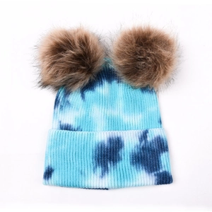 Détail de la maille côtelée tie-dye bleu avec deux pompons en fausse fourrure marron