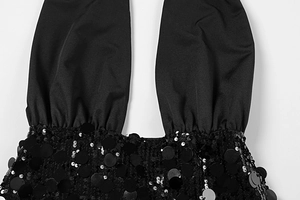 Detail of black halter dress featuring large round sequins and premium smooth fabric