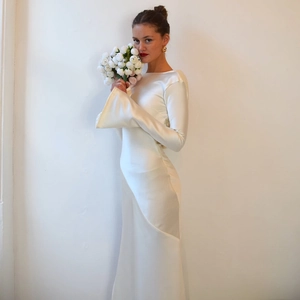 Detailed view of elegant white satin long-sleeve dress with smooth silk texture