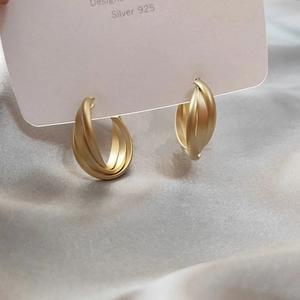 S925 silver needle gold geometric twisted hoop earrings with matte finish on silk background