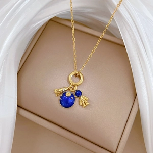 Gold space theme necklace featuring blue enamel planet, astronaut, and rocket charms