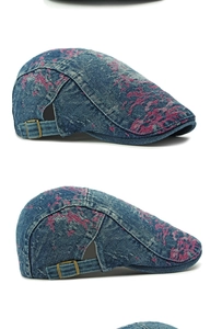 Detail of blue washed denim flat cap with floral embroidery and adjustable bronze buckle