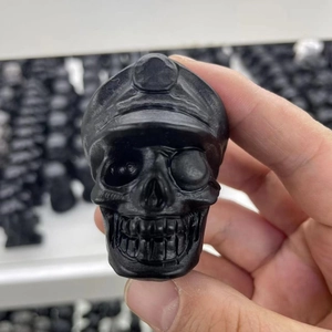 Detailed view of matte black obsidian-style skull figurine held by hand for scale