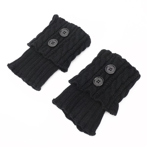 Close-up of black cable knit leg warmers featuring decorative round buttons on white background