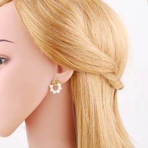Detailed view of a model wearing gold flower earrings with elegant pearls