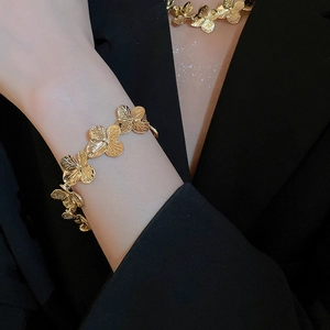 Close-up of a vintage golden four-leaf clover pendant necklace worn with a black suit