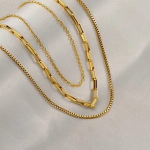 Macro shot of three-layer gold stainless steel necklace with various chain textures